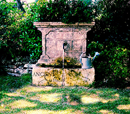 antique hand carved limestone leaf man head mask fountain with a demi-lune half cressant limestone basin reclaimed from the south of France Circa 17th century