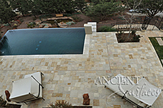 The 'Arcane stone' are ancient reclaimed limestone flooring tiles from the 17th century and later. Pavers in this photo are shown installed on a pool deck overlooking the bay in coastal Californian town